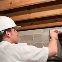 Termite inspection technician checking a basement wall and framing for termite activity in Nashville, TN