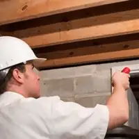 Termite inspection technician checking a basement wall and framing for termite activity in Nashville, TN